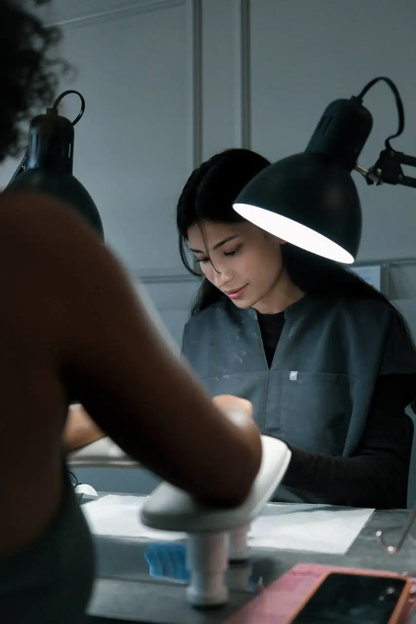 Nail tech at work under the lamp at No Choice Beauty Studio