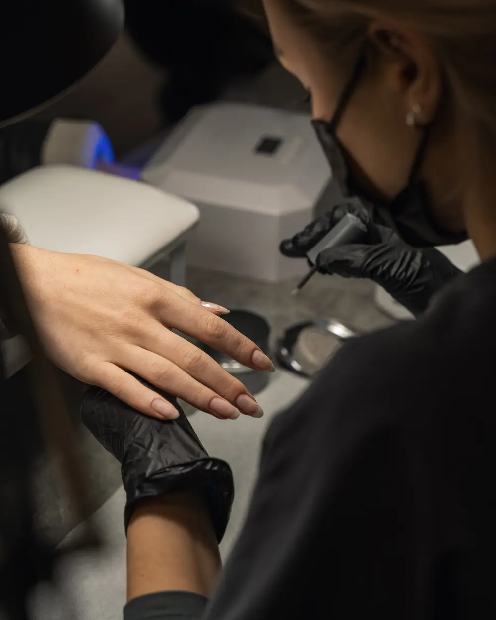 Tech applying an extension during a structured manicure