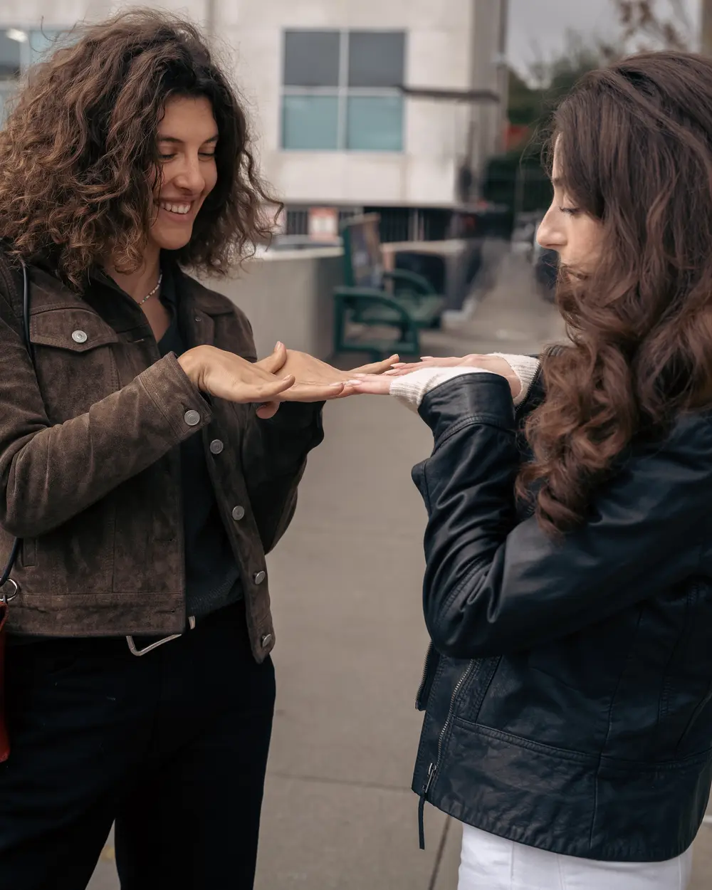 Two friends comparing fresh manicures outside the studio